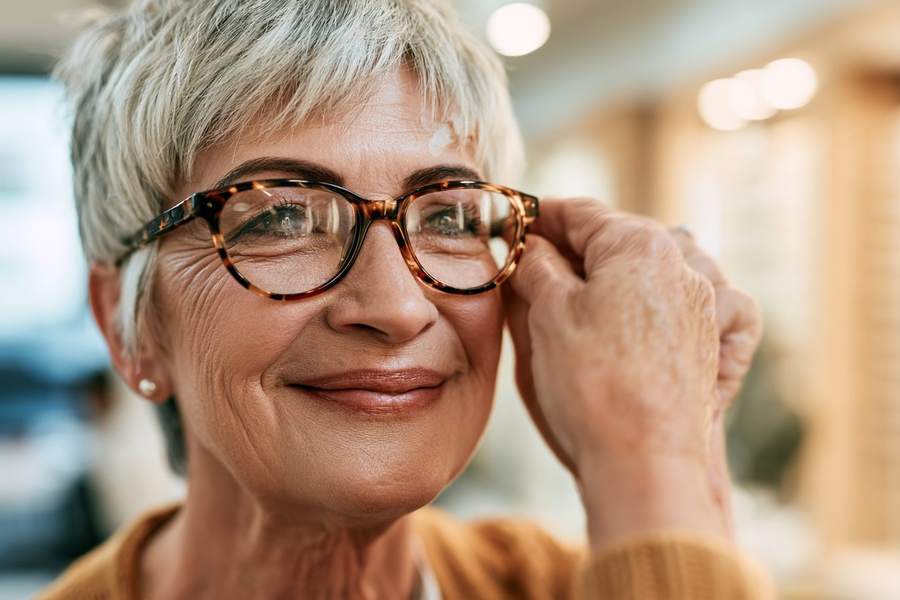 Lächelnde Frau rückt ihre neue Schildpatt-Brille zurecht